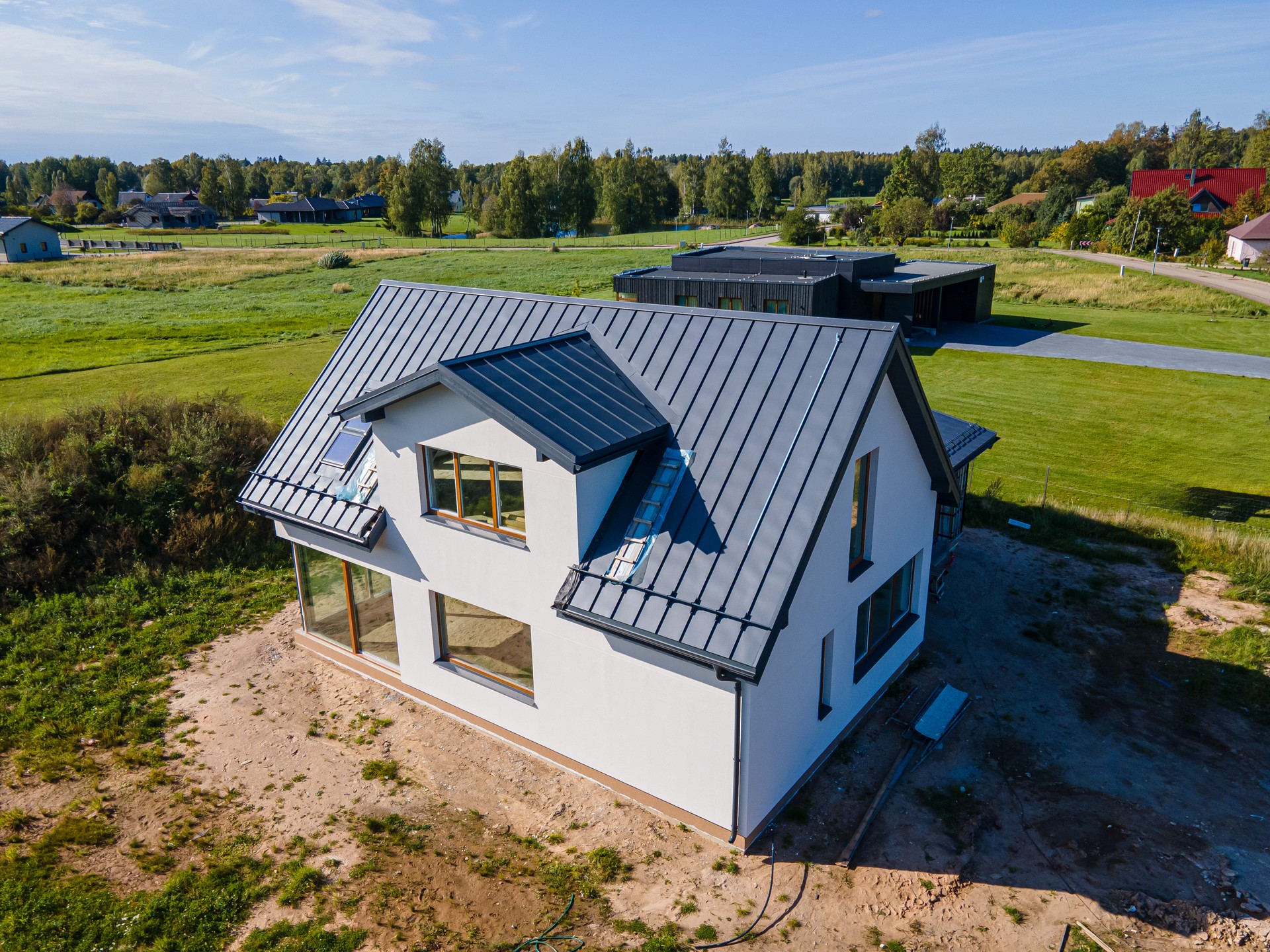 Modern new-build house with a metal roof and large windows in a rural setting